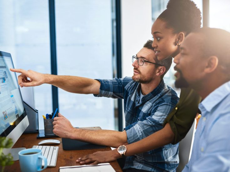 Cropped shot of three businesspeople working around a computer in the office